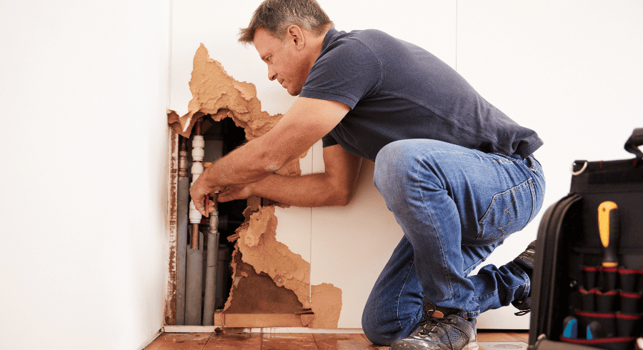 Plumber working in a home on water pipes.